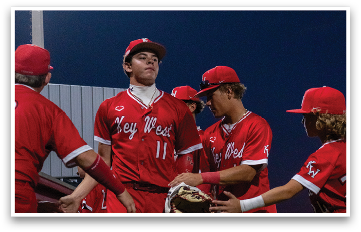 A group of baseball players wearing red uniforms are standing on a field. One player is holding a baseball glove. AI generated content
