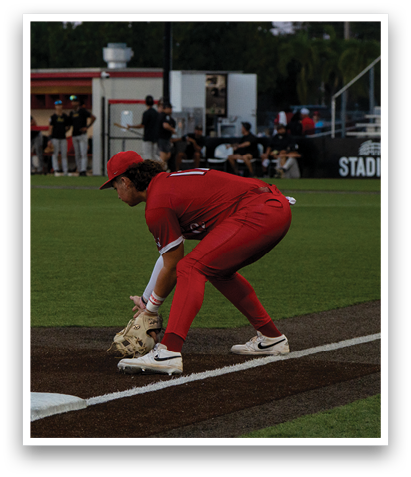 A baseball player in a red uniform is bending over to catch a ball. AI generated content