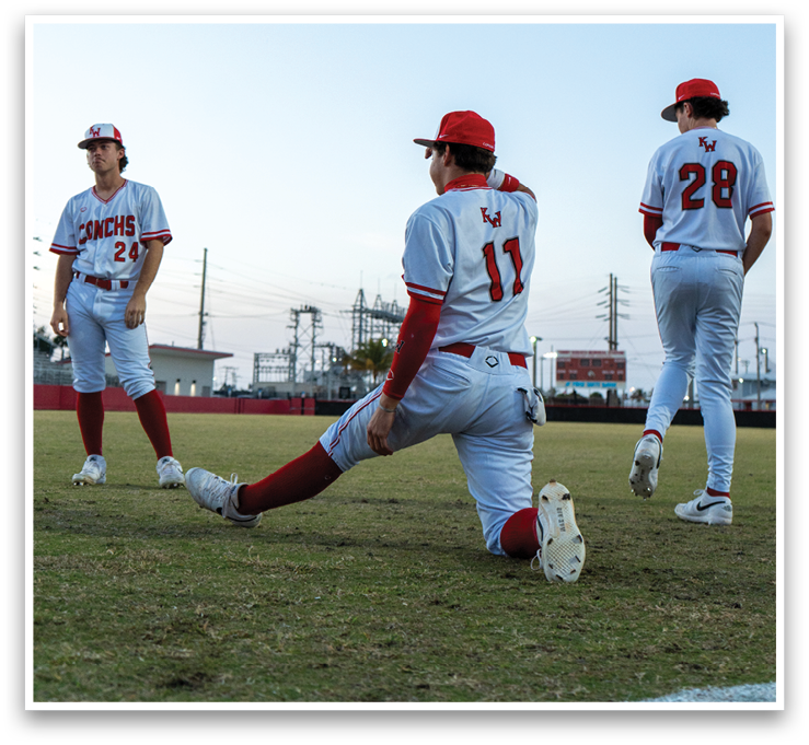 Three baseball players are standing on a field. One player is bending over, possibly stretching, while the other two players are standing nearby. AI generated content