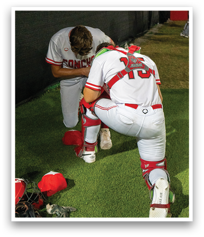 Two baseball players kneeling on the field, one with a red hat and the other with a white jersey. AI generated content