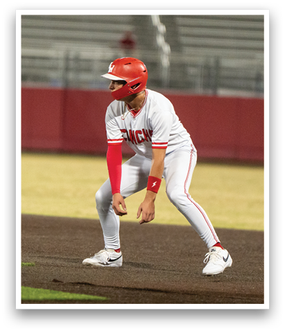 A baseball player in a white uniform is crouching on the field, holding a baseball bat. AI generated content