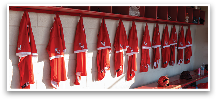 A red bench is in a room with a red shelf above it. The shelf is full of red shirts. AI generated content