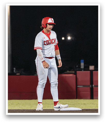 A baseball player in a white uniform with red trim is standing on a field. AI generated content