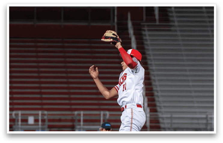 A baseball player in a red and white uniform leaps in the air to catch a ball. AI generated content