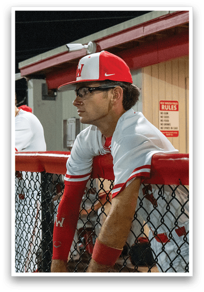 A man wearing a baseball uniform is leaning on a fence. AI generated content