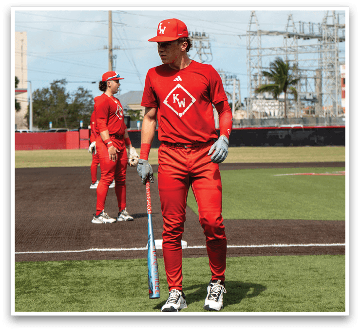 Two baseball players in red uniforms are standing on a field. One player is holding a bat and the other is wearing a baseball glove. AI generated content