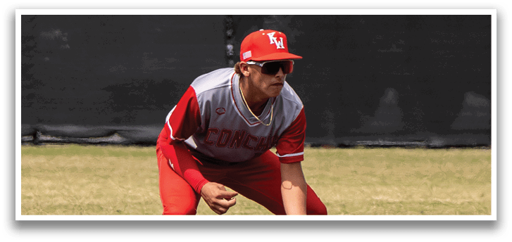 A baseball player wearing a red uniform and a red hat is crouching down on the field, holding a baseball glove. AI generated content