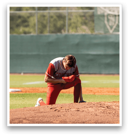 A baseball player is kneeling on the ground, holding his head in his hands. AI generated content