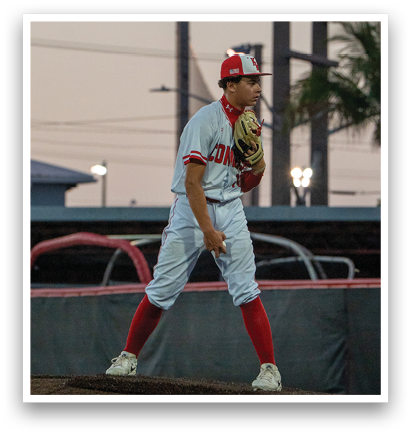 A baseball player in a red and white uniform stands on a field, holding a baseball glove. AI generated content