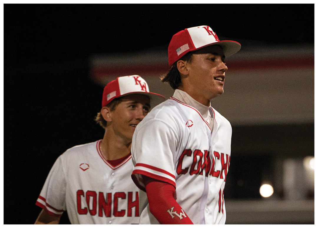 Two baseball players wearing red and white uniforms are standing on a field. One of the players is holding a baseball glove. AI generated content
