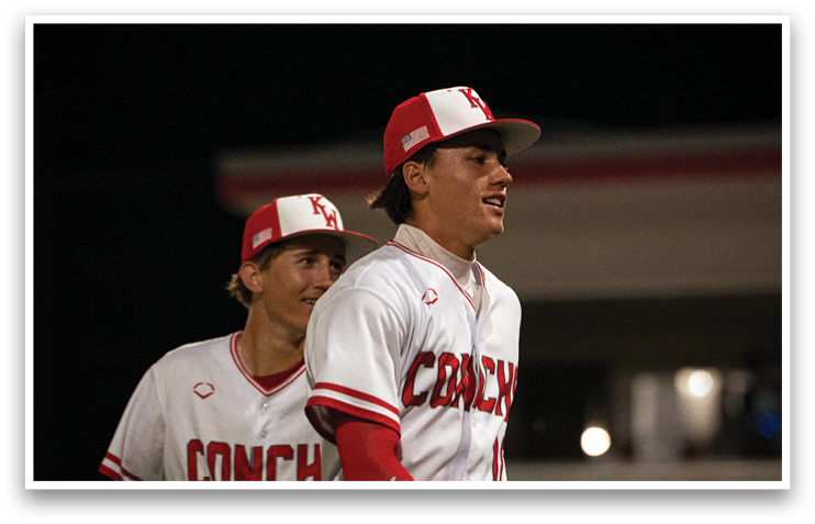 Two baseball players wearing red and white uniforms are standing on a field. One of the players is holding a baseball glove. AI generated content