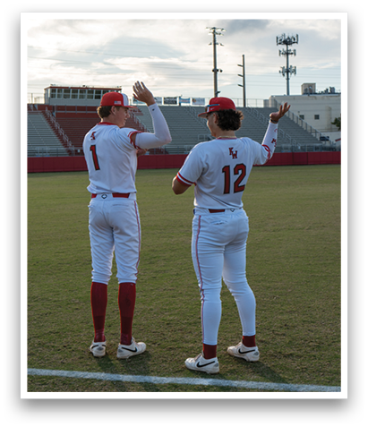 Two baseball players wearing white uniforms and red hats are standing on a field. AI generated content