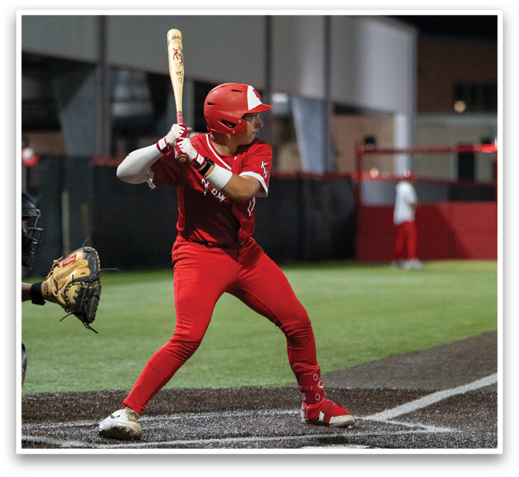 A baseball player in a red uniform is standing on a field. Description generated by AI