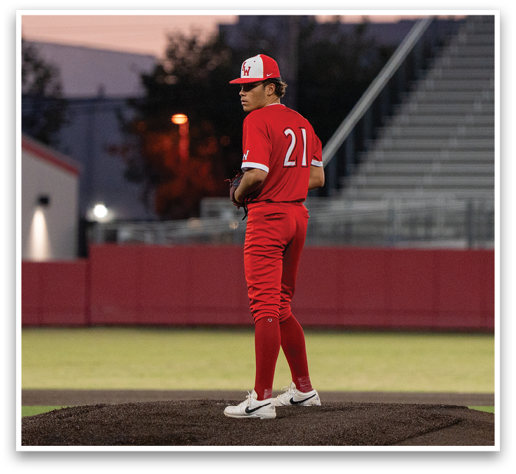 A baseball player wearing a red jersey and red pants is standing on a pitcher's mound. Description generated by AI