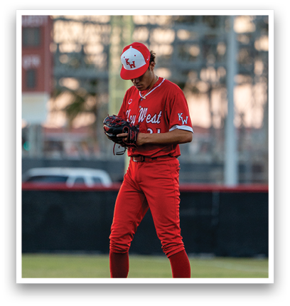 A baseball player in a red uniform stands on the pitcher's mound. Description generated by AI