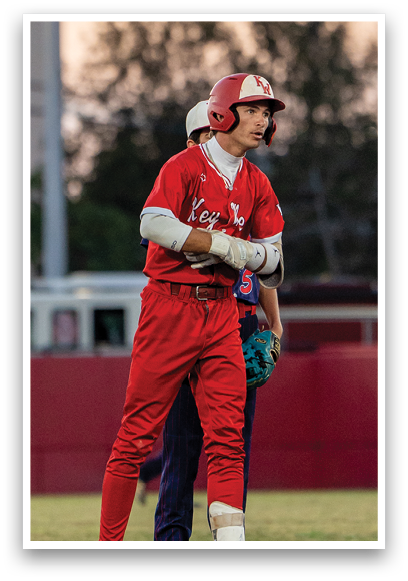 A baseball player in a red uniform is standing on a field. Description generated by AI