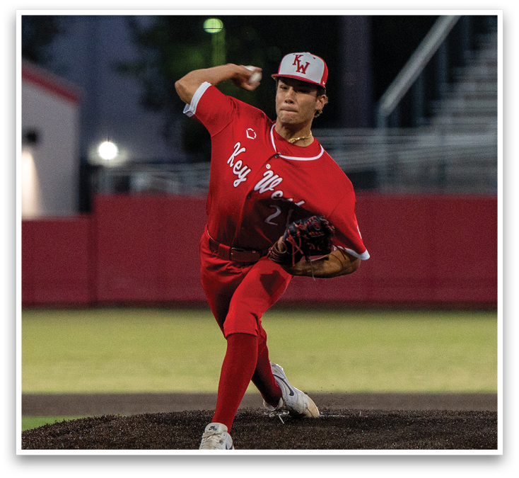 A baseball player in a red shirt and red pants is pitching a ball. Description generated by AI