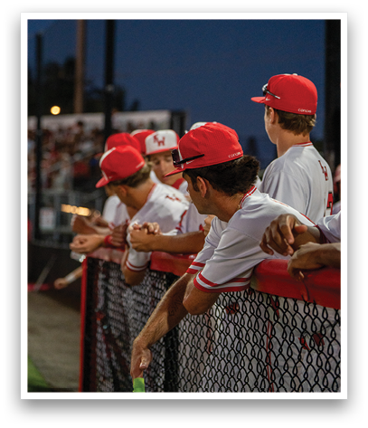 A group of baseball players wearing red hats and white uniforms. Description generated by AI