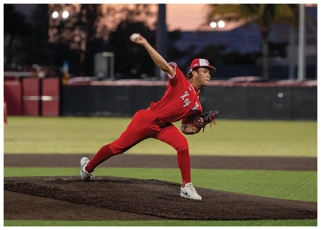 A baseball player in a red shirt and red pants is pitching a ball. Description generated by AI