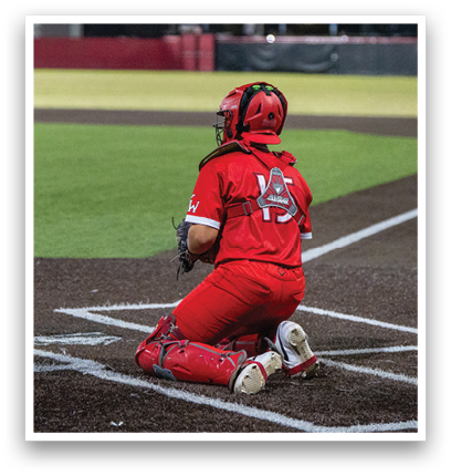 A baseball player wearing a red jersey and red pants is sitting on the ground. Description generated by AI