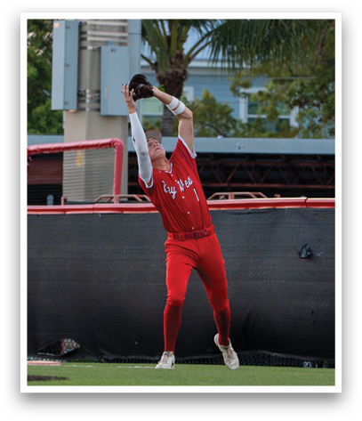 A baseball player wearing a red shirt and red pants catching a ball. Description generated by AI