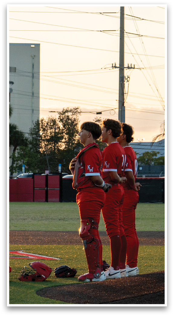 Three baseball players standing on a field. Description generated by AI