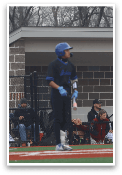 A baseball player in a blue helmet and black uniform stands on the field, holding a bat. AI generated content