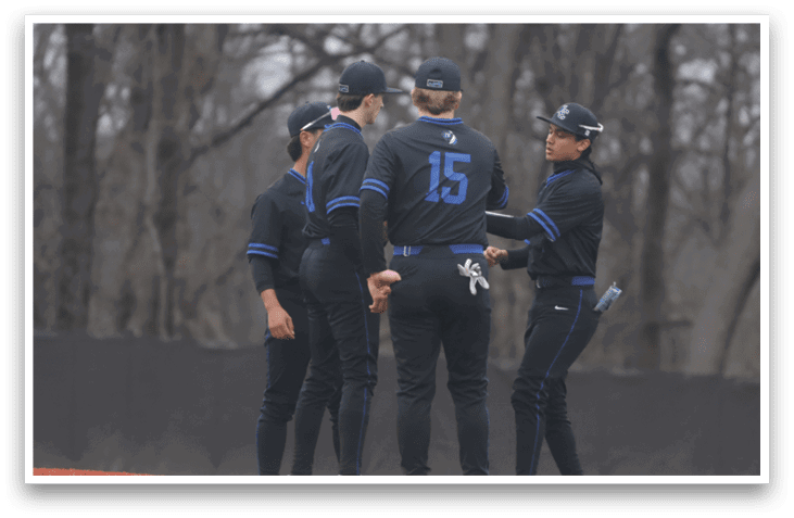 Four baseball players wearing black uniforms and blue numbers on their shirts are standing on a field. AI generated content