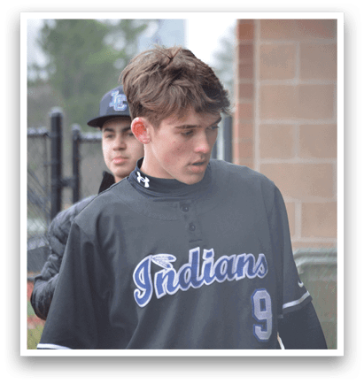 A man wearing a baseball uniform with the word Indian on the front walks past a fence. AI generated content