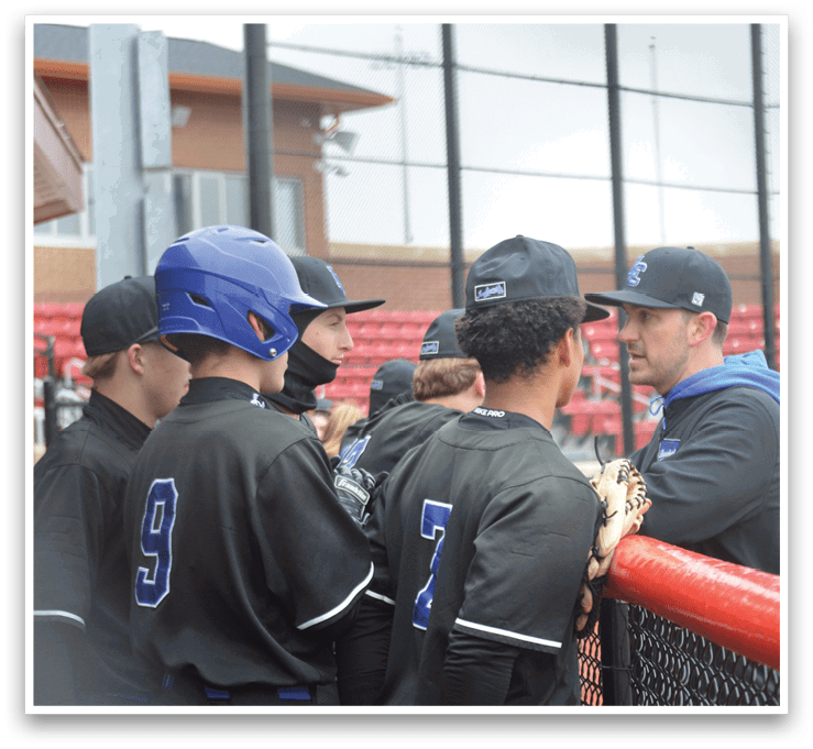 A group of baseball players wearing blue and black uniforms are standing around a fence. AI generated content