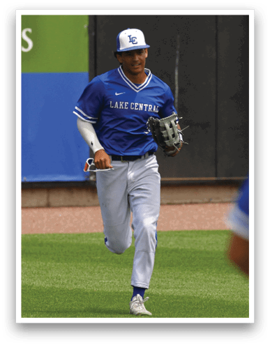 A person wearing a blue Lake Central baseball uniform and cap is running on a grassy field while holding a baseball glove. Description generated by AI