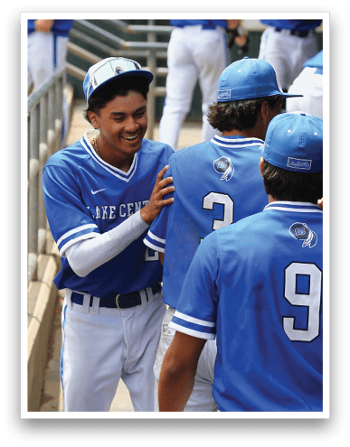 People wearing blue baseball uniforms and caps are gathered together, with some numbers visible on their backs. Description generated by AI
