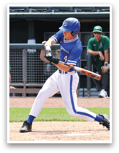 A person in a blue and white baseball uniform is swinging a bat to hit a baseball on a baseball field with a green grass outfield and a dugout in the background. Description generated by AI