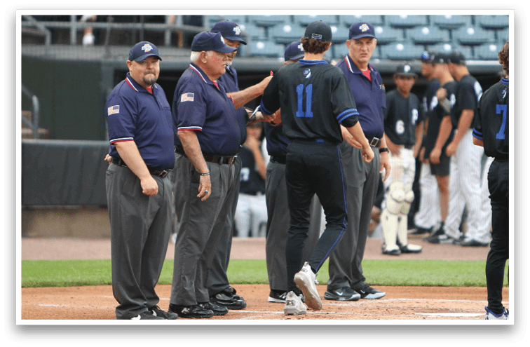 Several people in sports uniforms and umpire outfits stand on a baseball field near home plate during a game. Description generated by AI