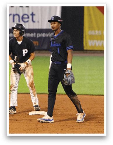 Three people stand on a baseball field near a base, with two wearing baseball uniforms and one in an umpire outfit. Description generated by AI