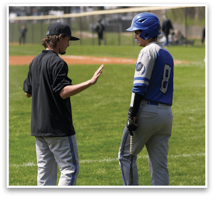 Two baseball players on a field, one wearing a blue and white uniform and the other wearing a black shirt. They are standing next to each other and talking. AI generated content