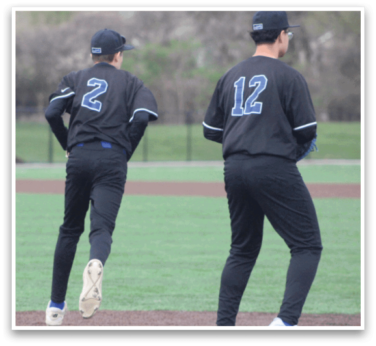 Two baseball players wearing black uniforms with the numbers 2 and 12 on the back are walking on a field. AI generated content