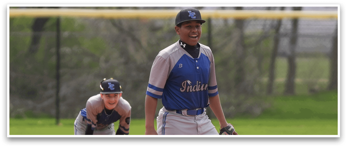 A baseball player in a blue and gray uniform is standing on the field, smiling and holding a baseball glove. Another player is kneeling nearby, also holding a baseball glove. AI generated content