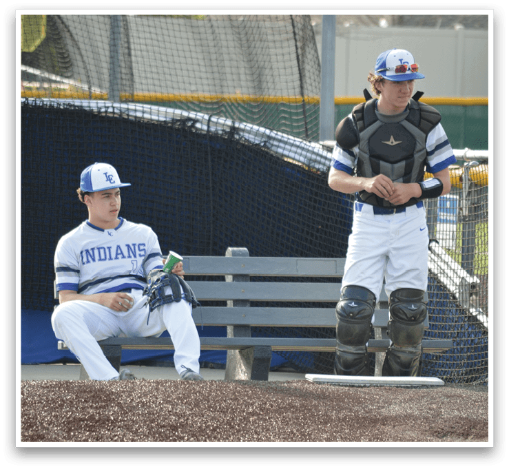 Two baseball players are sitting on a bench, one wearing a blue and white uniform and the other wearing a black and white uniform. They are both holding baseball gloves. AI generated content