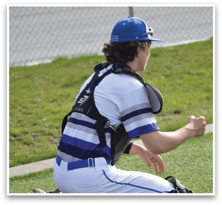 A person wearing a baseball uniform is kneeling on the grass. AI generated content
