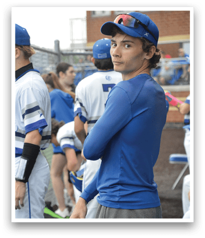 A man wearing a blue shirt and blue hat stands on a baseball field. AI generated content