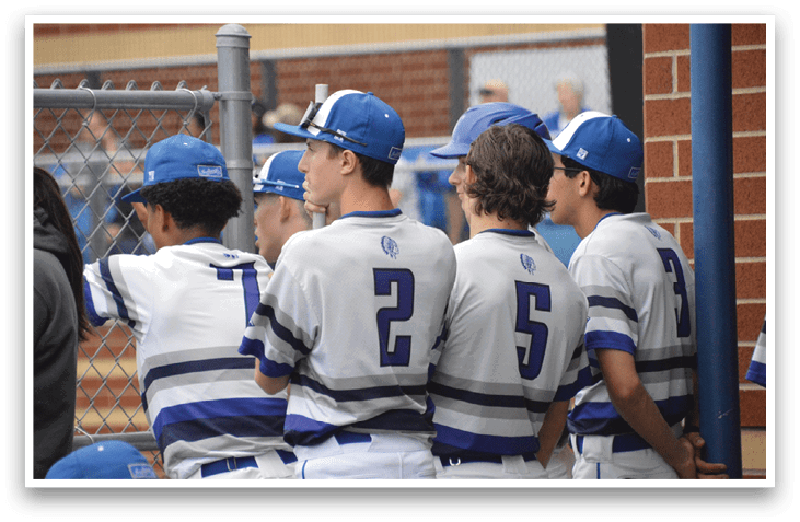 A group of baseball players wearing blue and white uniforms are standing next to a fence. AI generated content