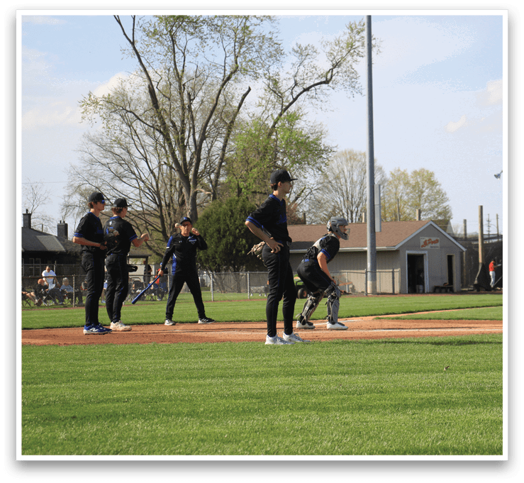 A baseball game is taking place with several players on the field. A man is standing in the dirt, holding a baseball bat, and another player is wearing a baseball glove. There are other players in various positions on the field, and a bench can be seen in the background. AI generated content