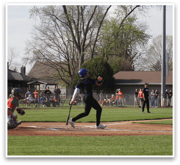 A baseball game is in progress with a batter at home plate, holding a bat and preparing to swing. A catcher is positioned behind the batter, wearing a baseball glove. There are several other people in the scene, likely teammates and opponents, watching the play unfold. The atmosphere is lively and competitive, as everyone focuses on the batter's next move. AI generated content