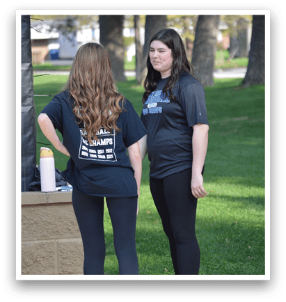 Two women wearing black shirts and leggings stand in a park. AI generated content