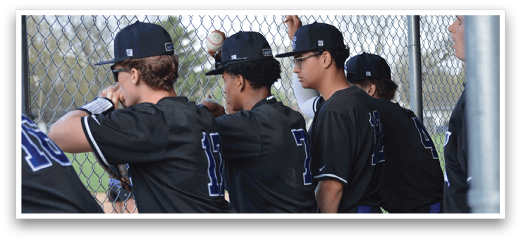 A group of young men wearing baseball uniforms are standing next to a chain link fence. AI generated content