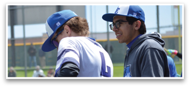 Two men are standing next to a fence, one of them wearing a baseball uniform. AI generated content