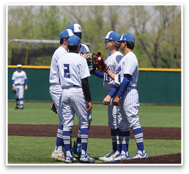 Four baseball players wearing white uniforms and blue socks are standing on a field. They are talking to each other and one of them is holding a baseball glove. AI generated content