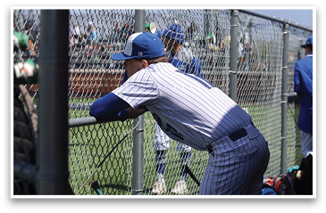 A baseball player wearing a blue and white uniform leans against a fence. AI generated content