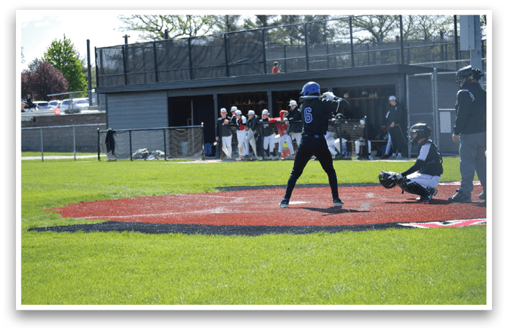 A baseball player is holding a bat, ready to swing. Description generated by AI